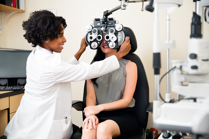 Woman sitting for an eye examination while the doctor checks her test.